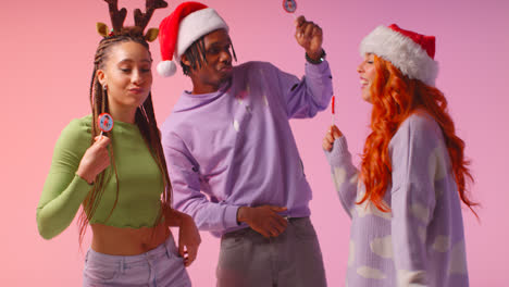 Studio-Shot-Of-Gen-Z-Friends-Dancing-At-Christmas-Party-Wearing-Santa-Hat-And-Reindeer-Antlers-1